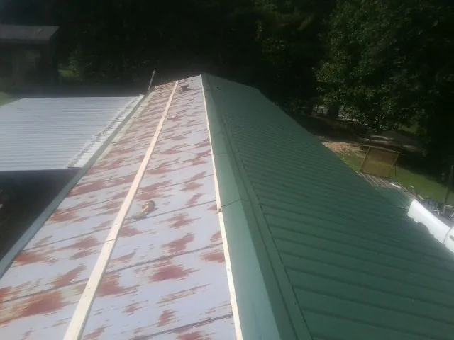 Old rusted panels beside newly installed green metal roofing — Wind Damage Roof Repair by Roofing Brothers in Orland