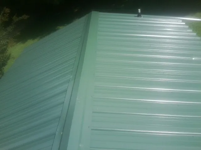 New green metal panels meeting at the ridge of a roof — Flat Roof Repair work by our crew in Orland
