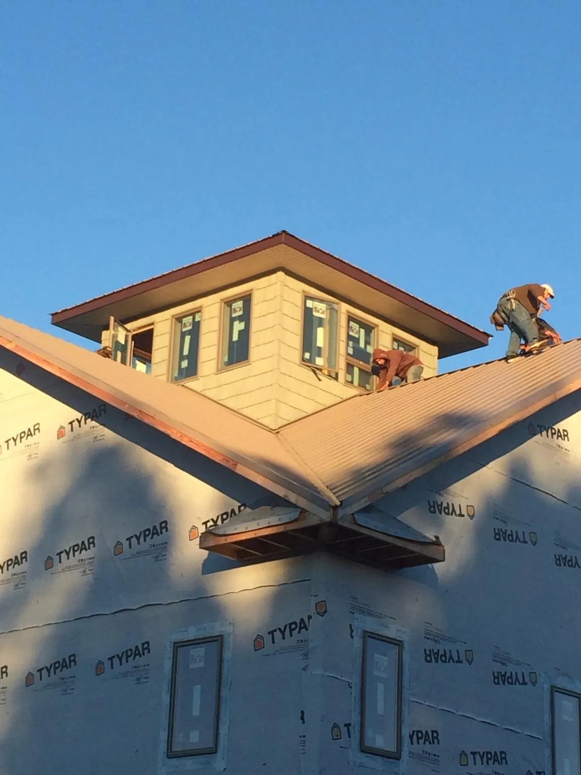 Roofers working around a rooftop cupola on a new metal roof at sunset — Roof Waterproofing in Orland by Roofing Brothers